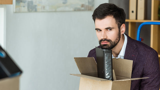 Stock photo showing a fired male employee sitting at his desk