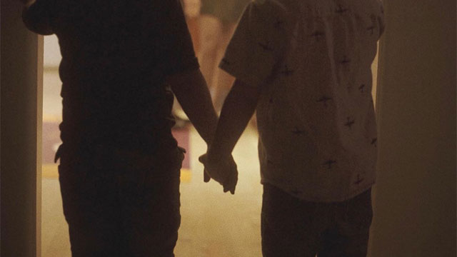 Two young boys holding hands in Christopher Sorensen's music video, "Way. Way. Back"