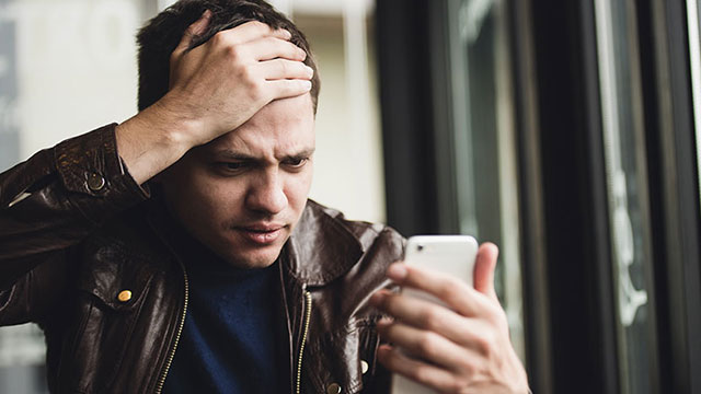Stunned man stares at his phone