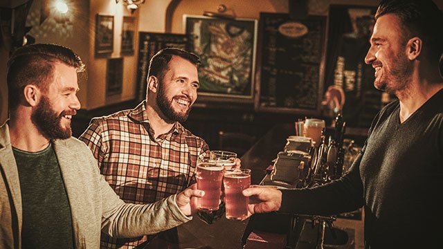 Men drink beer at a gay bar (image via Depositphotos)