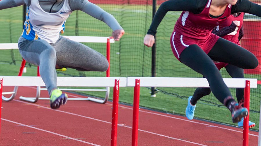 high school girls running track hurdles